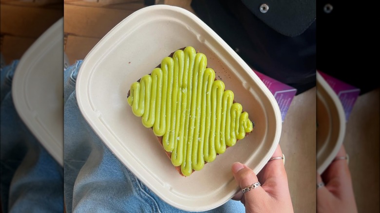 Hand holding a plate with kaya toast