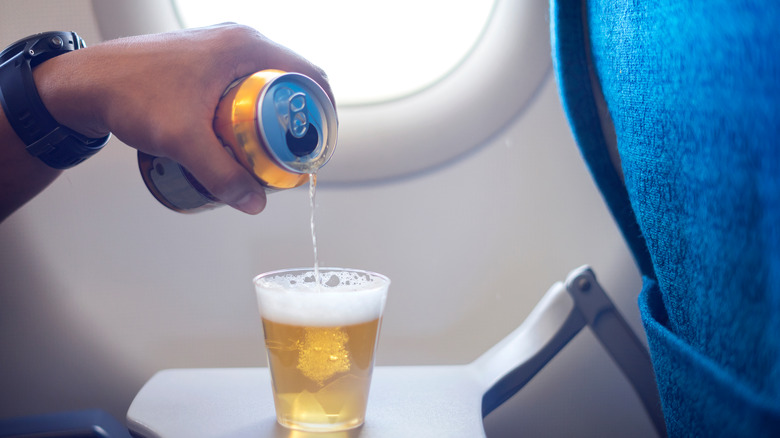 Man drinking beer in air plane