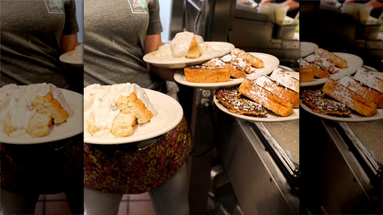 Server carries four plates of French toast and biscuits