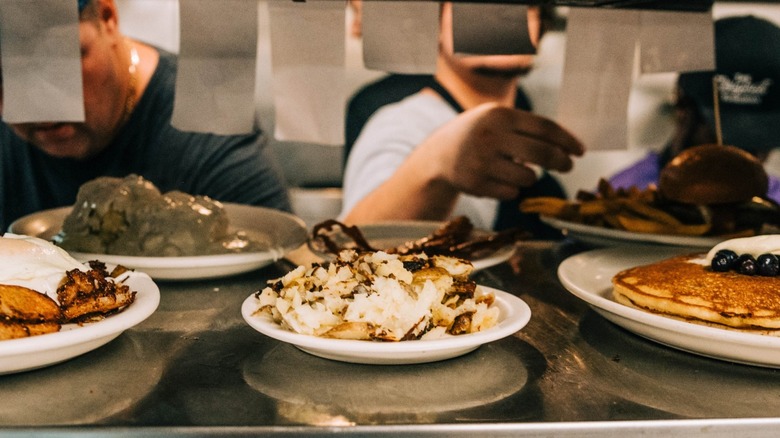 Plates of food on metal shelf in restaurant kitchen
