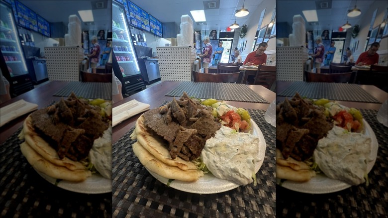 Plate of gyros, bread, salad, and sauce on table