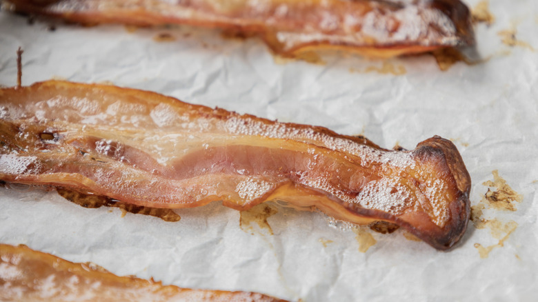 Straight, crispy bacon fresh from the oven on parchment paper in a cooking tray