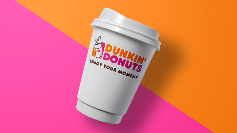 Dunkin' coffee cup on orange and pink background