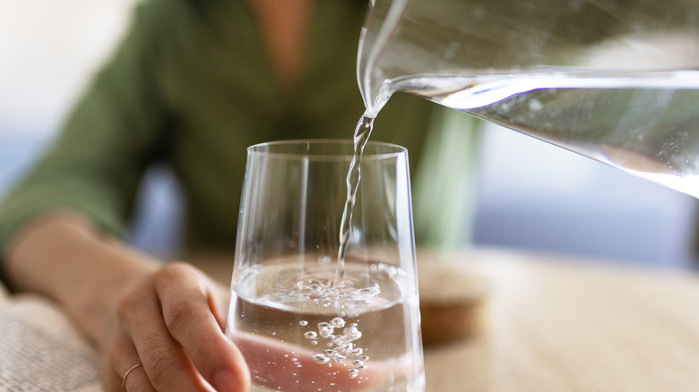 Woman pouring water from a jug into a glass