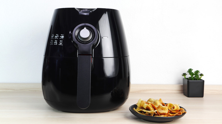 Air fryer on counter with plate of chips