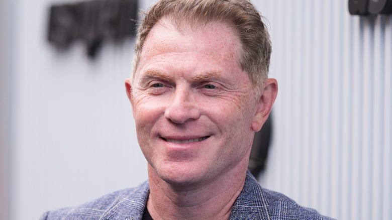 Bobby Flay smiling and wearing a gray blazer