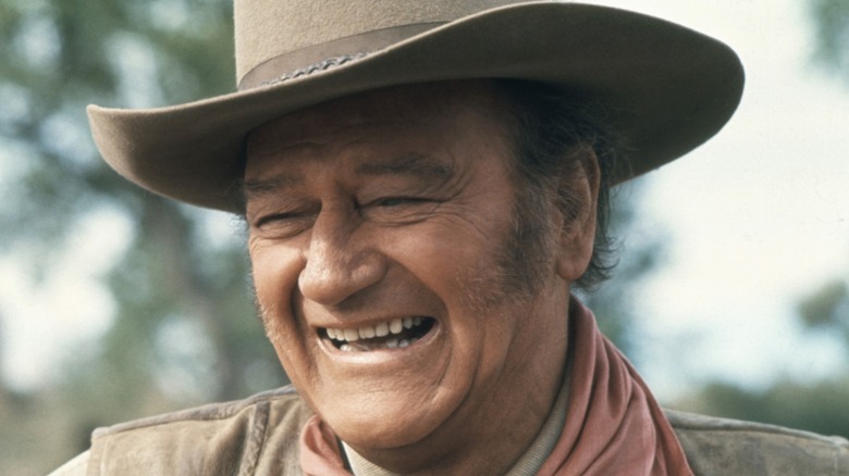 John Wayne smiling in cowboy costume.