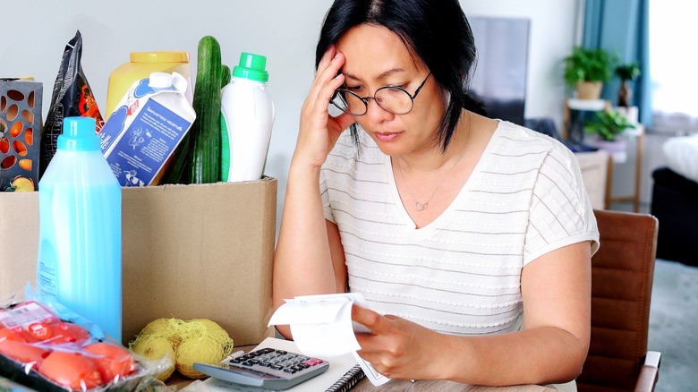Stressed woman budgeting groceries 