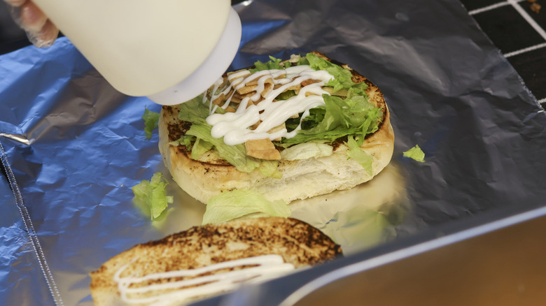 Mayonnaise being applied to a burger