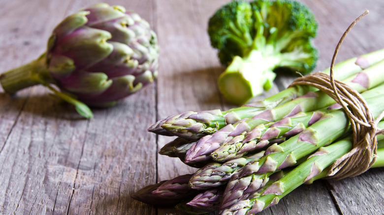 Asparagus, broccoli, and artichoke on a wooden table
