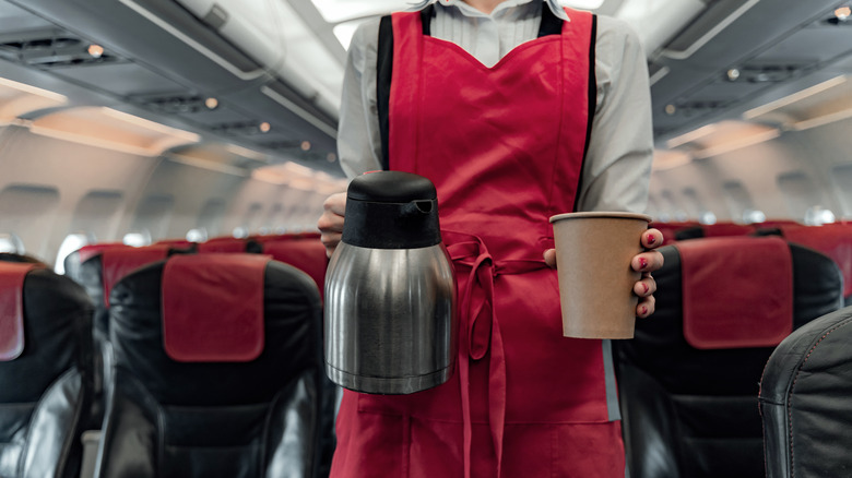 Flight attendant holding coffee carafe and a paper cup