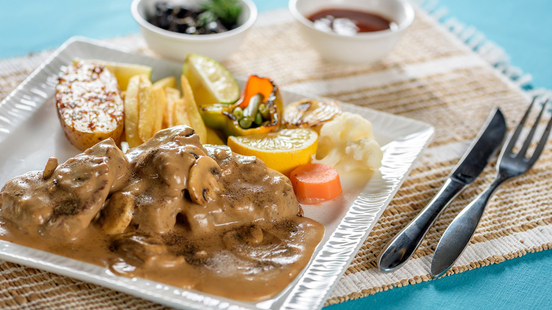 A steak with mushroom sauce on a white plate