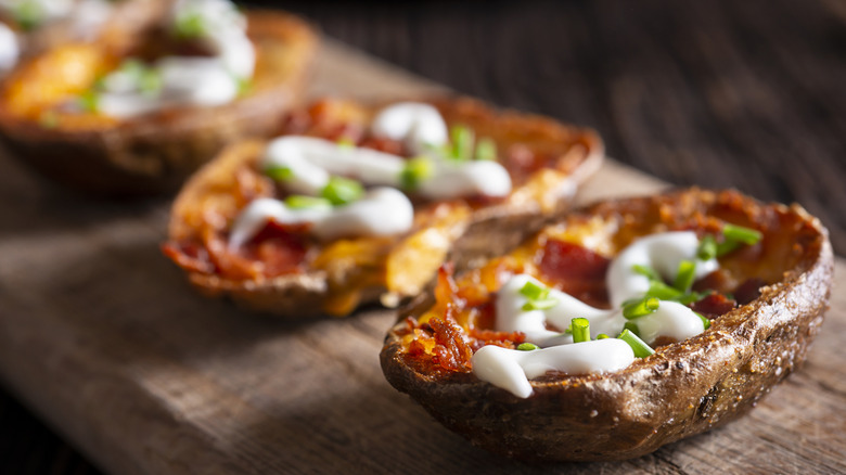 Closeup of baked potato skin with chives and sour cream