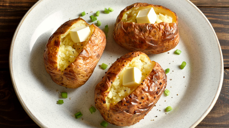Baked potatoes cut open with butter on top