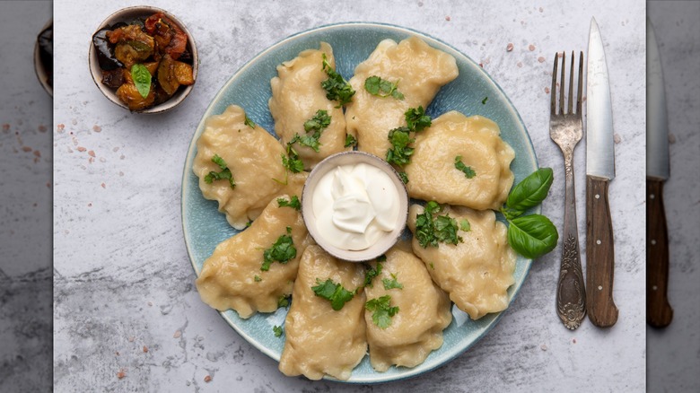 Pierogi on a plate with fresh herbs and dip
