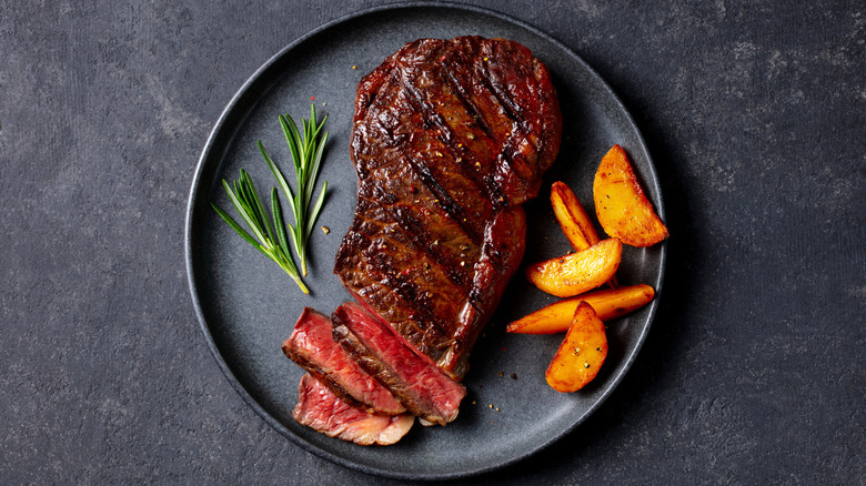 Steak on plate with garnish and potato wedges