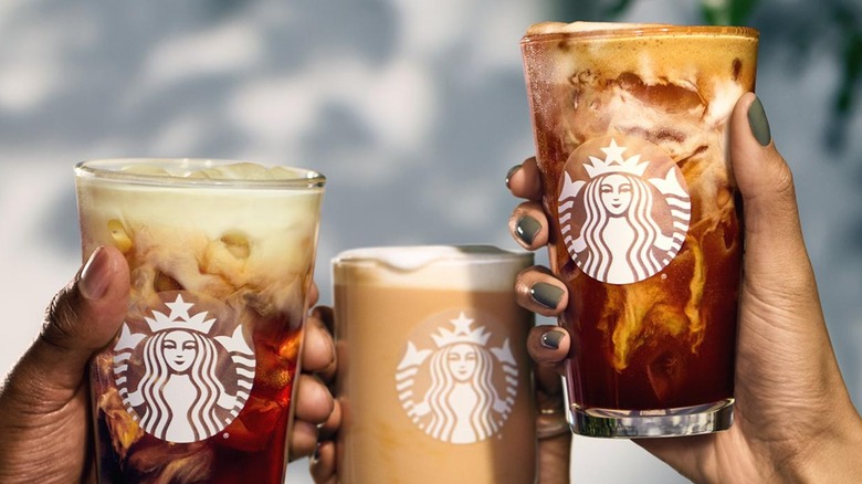 Three people holding Starbucks coffee