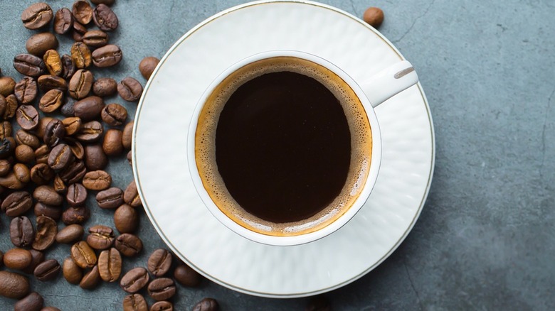 Cup of coffee next to coffee beans