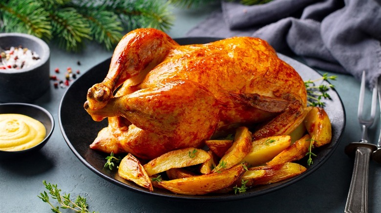 Roast chicken on black plate with home fries.