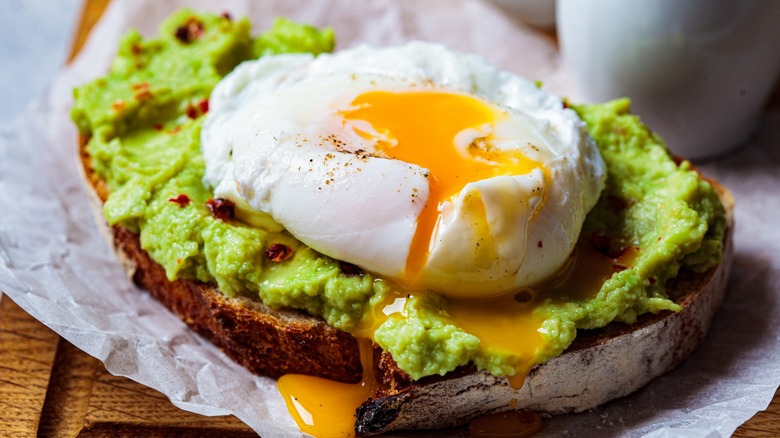 Runny poached egg on top of avocado toast