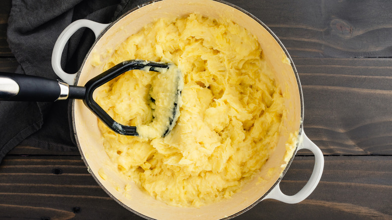 Potatoes and masher in pot