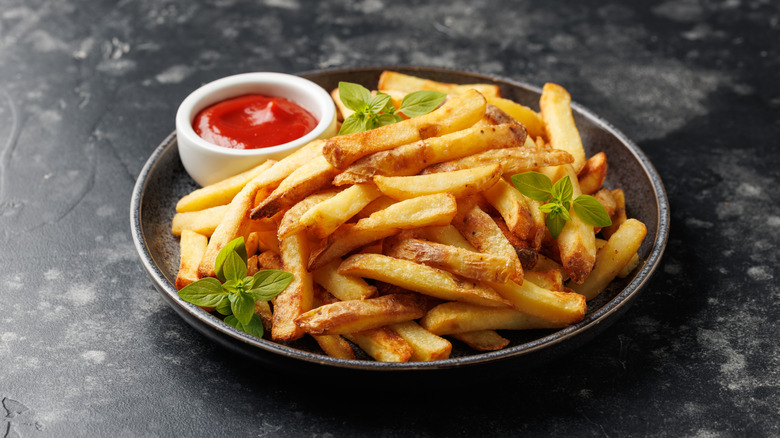 A bowl full of french fries with ketchup