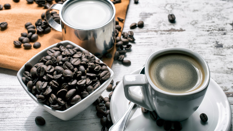 Espresso and fresh coffee beans with steamed milk on a table