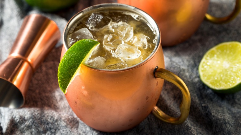 Kentucky mule served in copper cup and garnished with lime wedge, and a copper jigger and lime slice