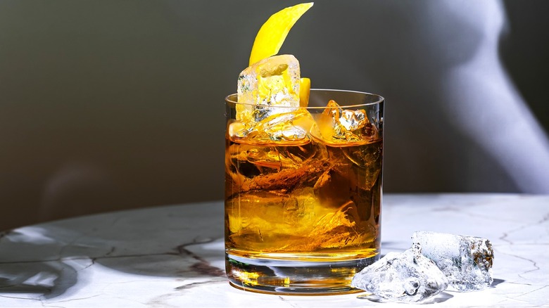 Bourbon-based cocktail served on the rocks and garnished with lemon peel on a table.