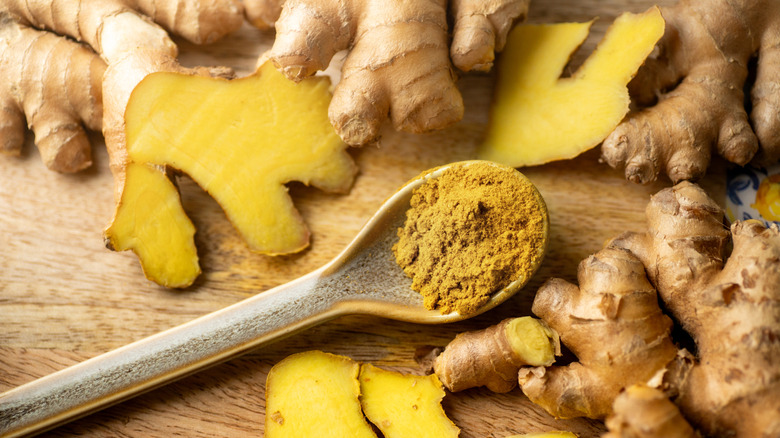 Sliced ginger beside a spoon of ground ginger