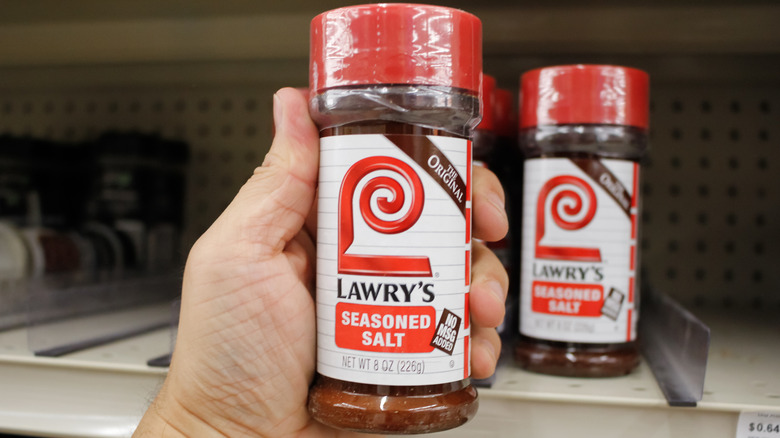 A hand pulling a jar of Lawry's seasoned salt off of a grocery shelf