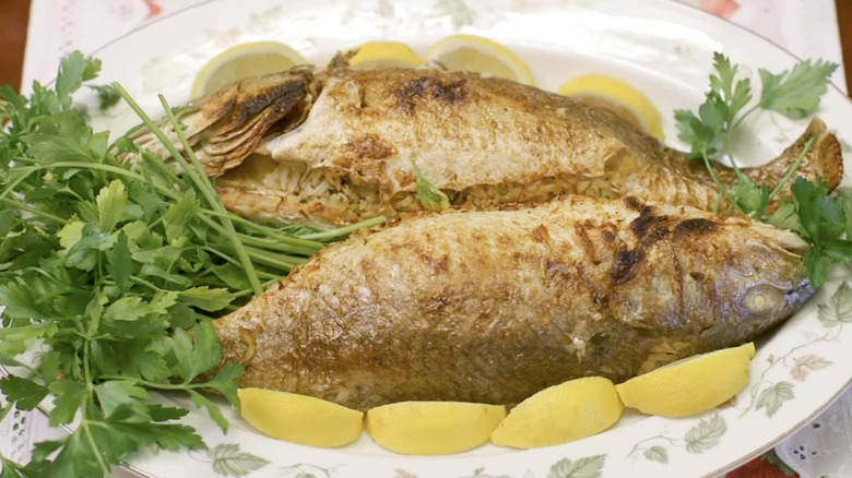 Pair of rice-stuffed fish on platter with lemon slices