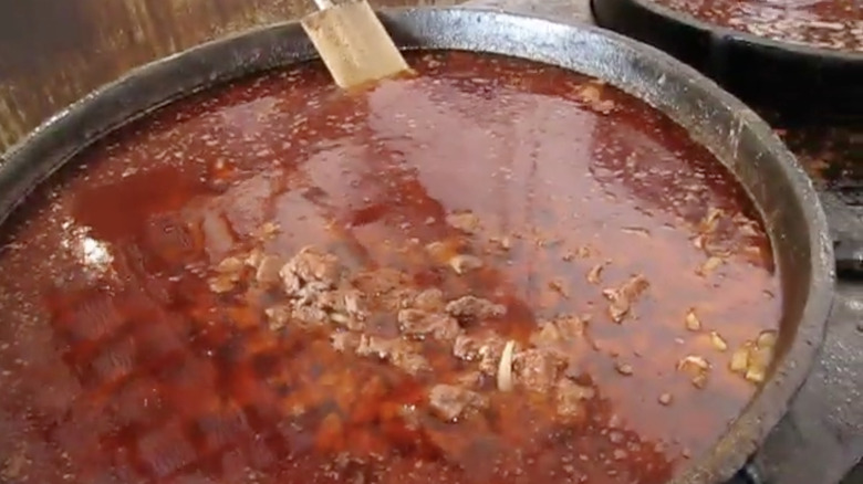 Vats of red broth picnic stew cooking