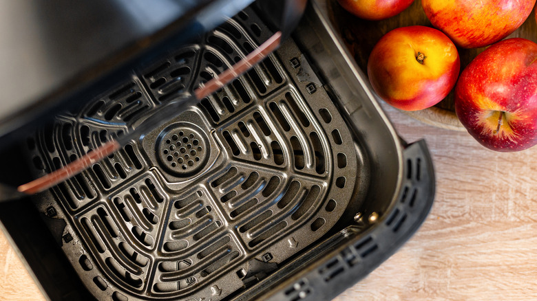 Open air fryer basket next to apples.