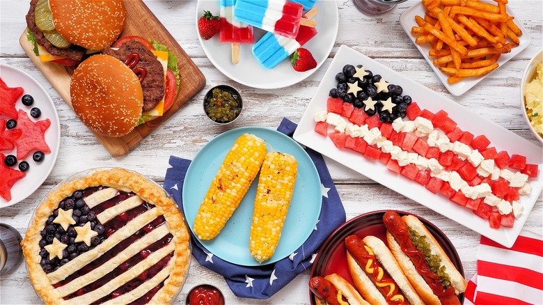 fourth of july spread with burgers, corn, pie, fruit