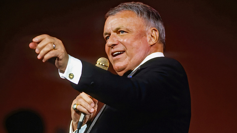 Frank Sinatra singing into microphone on stage in the 1990s.