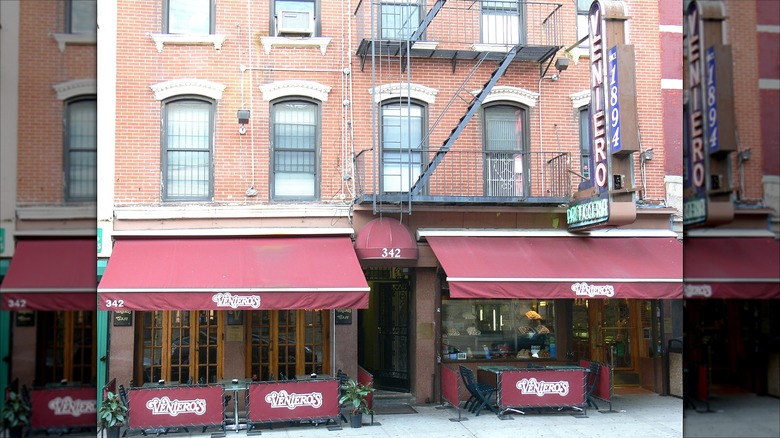 Outside of Veniero's, a brick building with maroon awnings at street level.