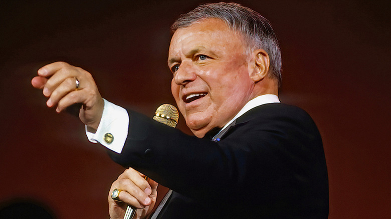 A smiling Frank Sinatra with hand outstretched