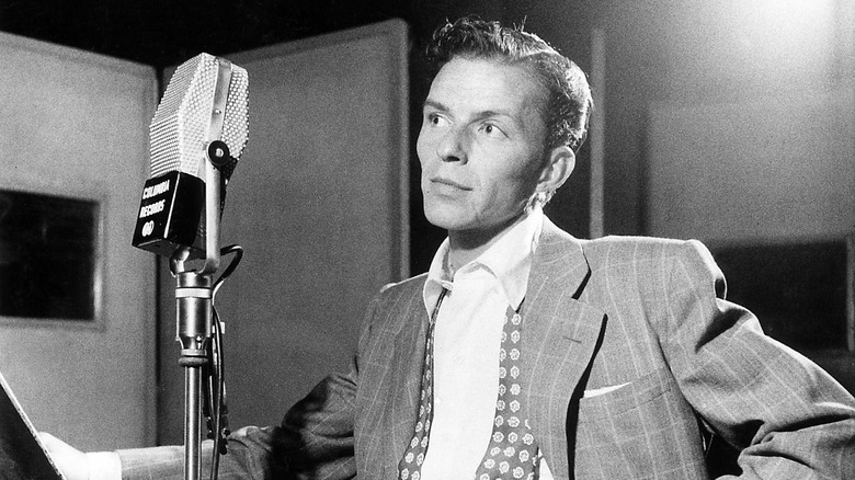 Black and white image of young Frank Sinatra behind microphone