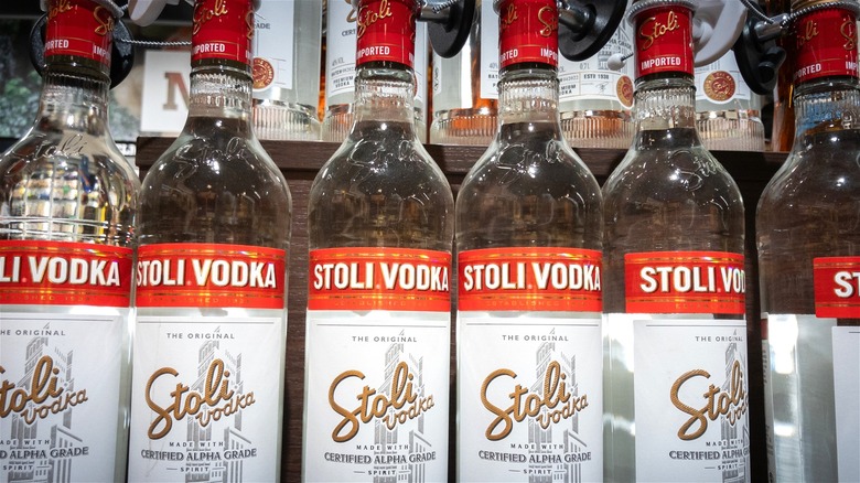 Bottles of Stoli vodka line a liquor store shelf.