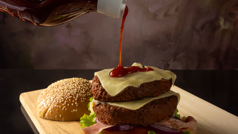 Pouring ketchup on a burger