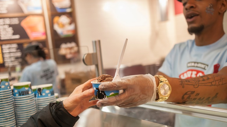 Scooper at Ben & Jerry's giving ice cream to customer.