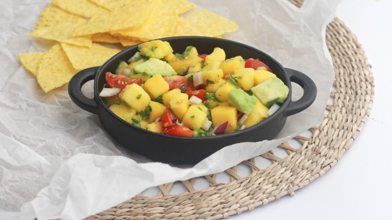 Tortilla chips on a plate with mango salsa and half a lime