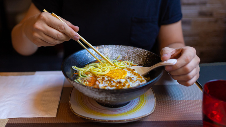 man eating eggs with ramen