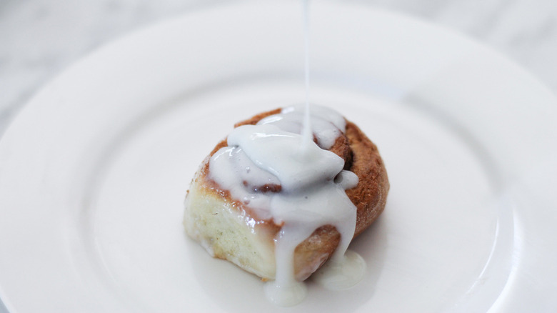 icing drizzling onto cinnamon roll