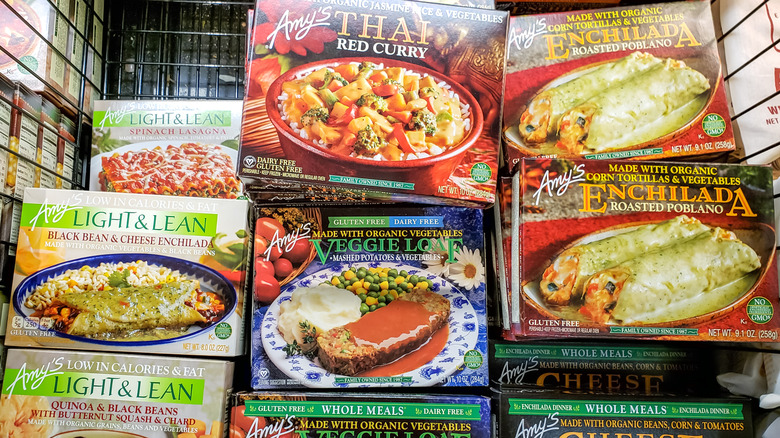Boxes of Amy's Kitchen frozen dinners are stacked in a grocery store cooler.