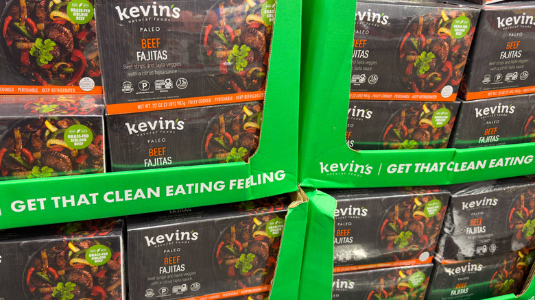 Boxes of Kevin's Natural Foods beef fajitas are stacked in a grocery store cooler.