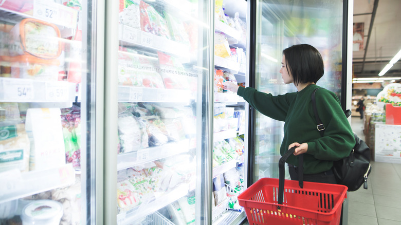 A woman shops for food in the frozen meals aisle