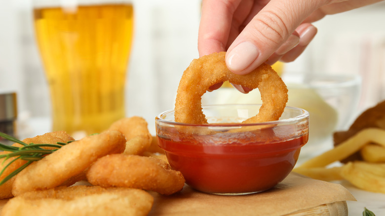 Dipping onion rings in ketchup