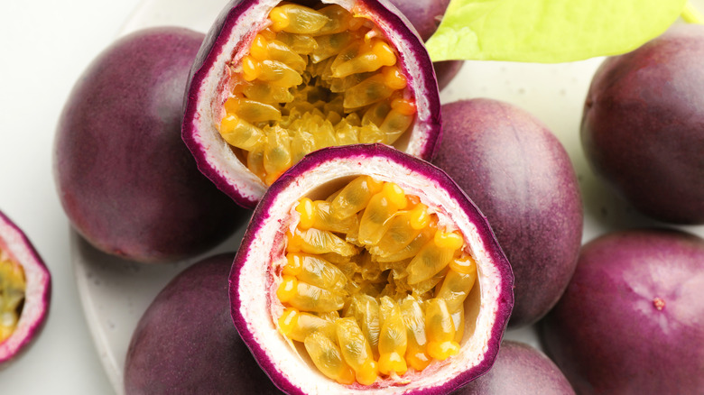 Halved passion fruit on top of whole purple ones